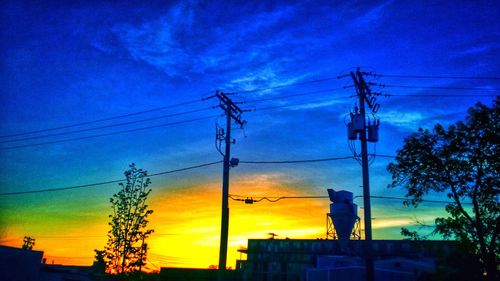 Low angle view of electricity pylon at sunset