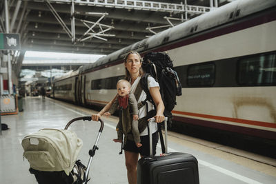 Mother with baby and luggage waiting at train station