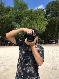 Young man photographing from camera at beach