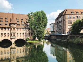 Arch bridge over canal amidst buildings in city against sky