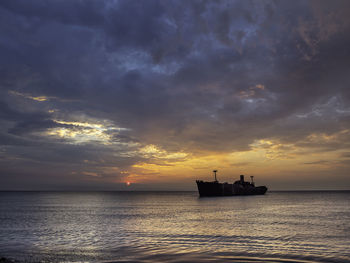 Silhouette boat in sea against sky during sunset