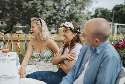 Happy male and female friends having fun while sitting at table during dinner party