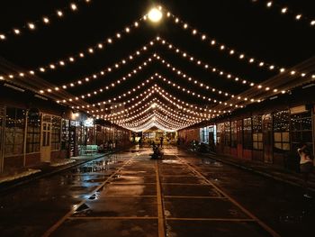 Illuminated street against sky at night