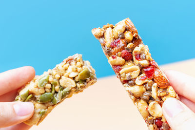 Female hands hold a protein bars on a blue and brown background.