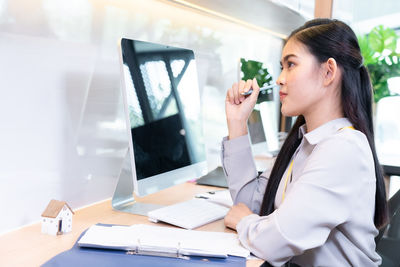 Side view of young woman using mobile phone at table
