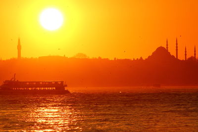 Passenger crafts sailing in strait by silhouette suleymaniye mosque against sky during sunset