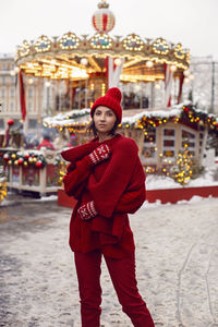 Woman in a red warm sweater, hat in winter, red square in moscow against the background carousel