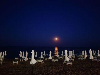 Chairs on beach against clear sky at night