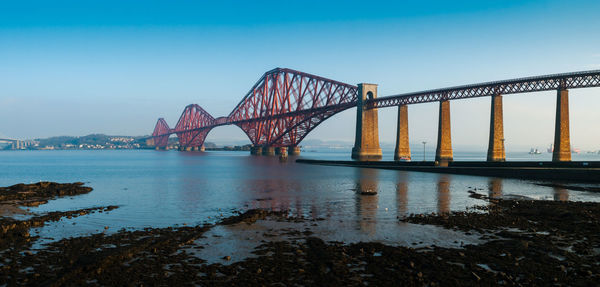 Bridge over calm lake against clear sky