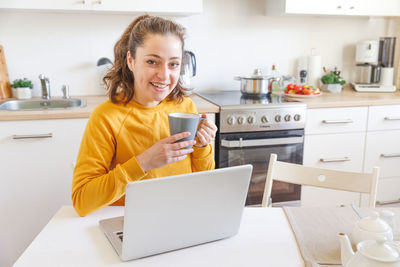 Portrait of young woman using digital tablet while sitting at home