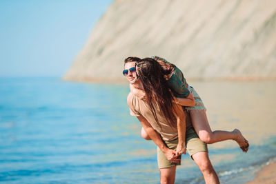 Man carrying woman on back at beach