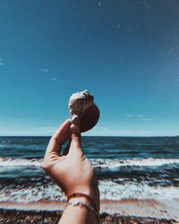 Midsection of person holding sea against sky