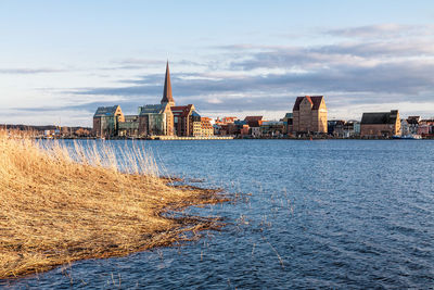 Sea by cityscape against sky