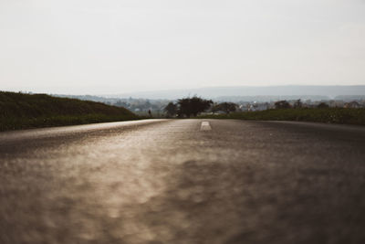 Surface level of road amidst field against clear sky