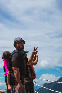 Bearded father with her toddler daughter in baby carrier on back outside in mountain nature.