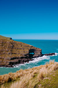 Scenic view of sea against clear blue sky. cave ,rocks