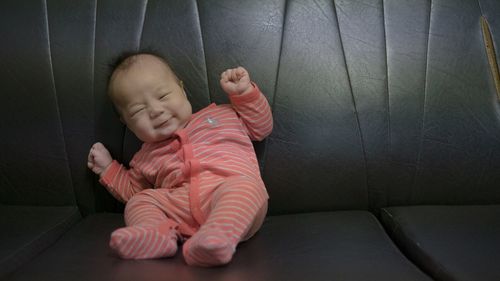 Full length of cute smiling baby boy on leather sofa