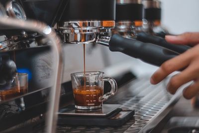 Midsection of man pouring coffee in cafe