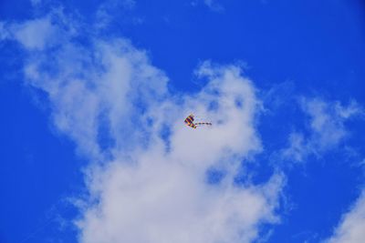 Low angle view of airplane flying against blue sky