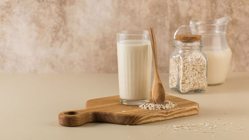 A glass of oat milk, a jug and oat flakes. the concept of alternative lactose-free dairy products. 