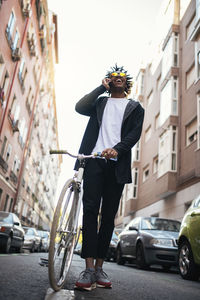 Man walking with bicycle while using phone on road