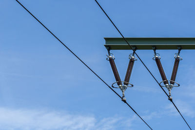 Low angle view of electricity pylon against blue sky