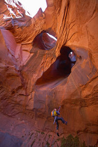 Man rappelling into cave at escalante's giant staircase