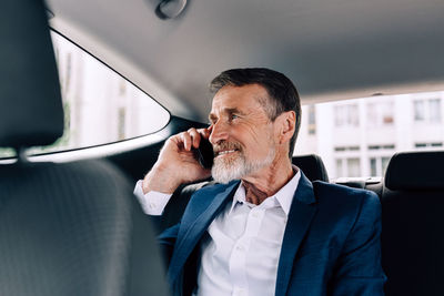 Midsection of man using mobile phone in car