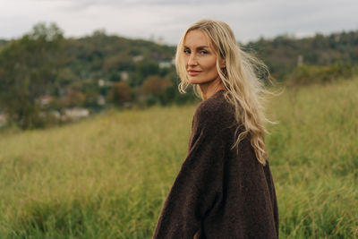 Portrait of young woman standing on field