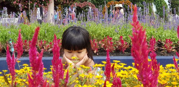Cute girl sitting against flowering plants