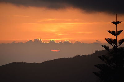 Scenic view of silhouette mountains against orange sky