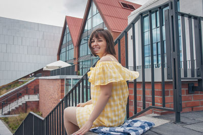 Portrait of smiling woman sitting against building