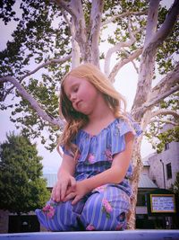 Girl sleeping while sitting against tree