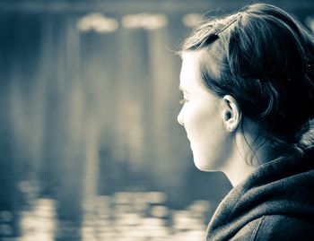 Close-up of thoughtful woman with lake in background