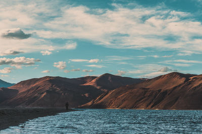 Scenic view of lake by mountains against sky