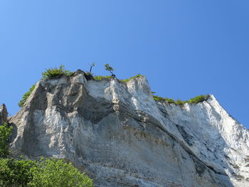 Low angle view of rock against clear blue sky