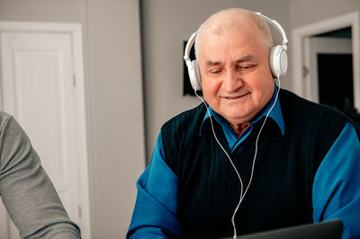 Senior man wearing headphones sitting at home