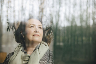 Thoughtful businesswoman looking through window at workplace