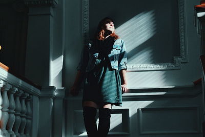 Woman standing against wall at home