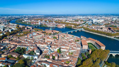 High angle view of town by sea against blue sky