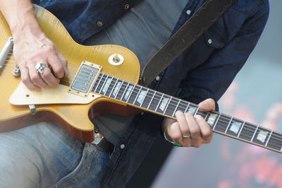 Midsection of man playing guitar