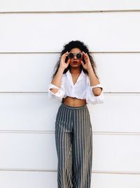 Fashionable young woman standing against wall