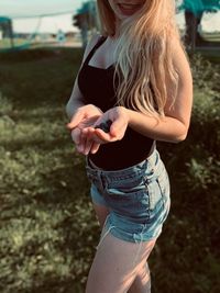 Midsection of woman holding blueberries while standing on field