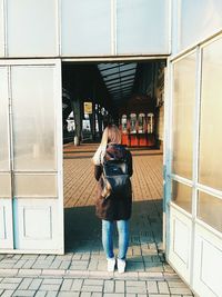 Rear view of woman standing at entrance of railroad station