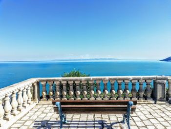 Deck chairs on beach against clear blue sky