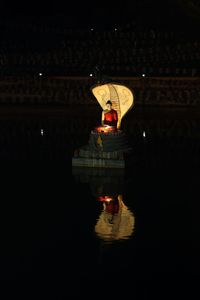 Illuminated building by river at night