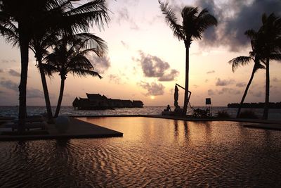 Swimming pool by sea against sky during sunset