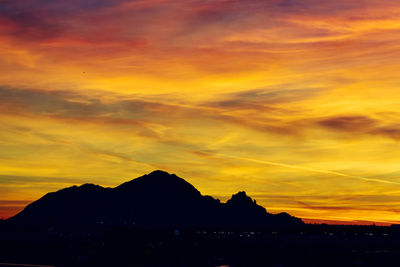 Silhouette mountains against dramatic sky during sunset