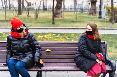 Full length of woman sitting on bench in park