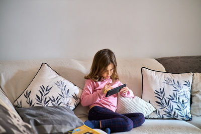 Rear view of woman sitting on sofa at home